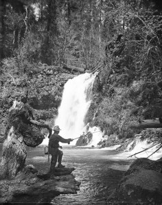 photo of fisherman casting at foot of falls